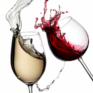Two wine glasses, one filled with white wine and the other with red wine, clink together, causing the wine to splash dramatically in mid-air against a white background.
