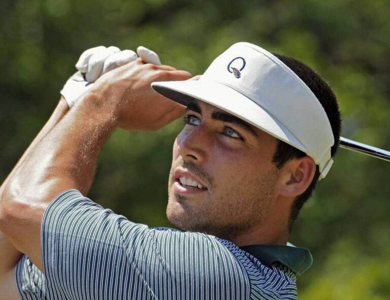 A young man wearing a white visor and striped golf shirt holds a golf club mid-swing, looking into the distance on a sunny day with greenery in the background.